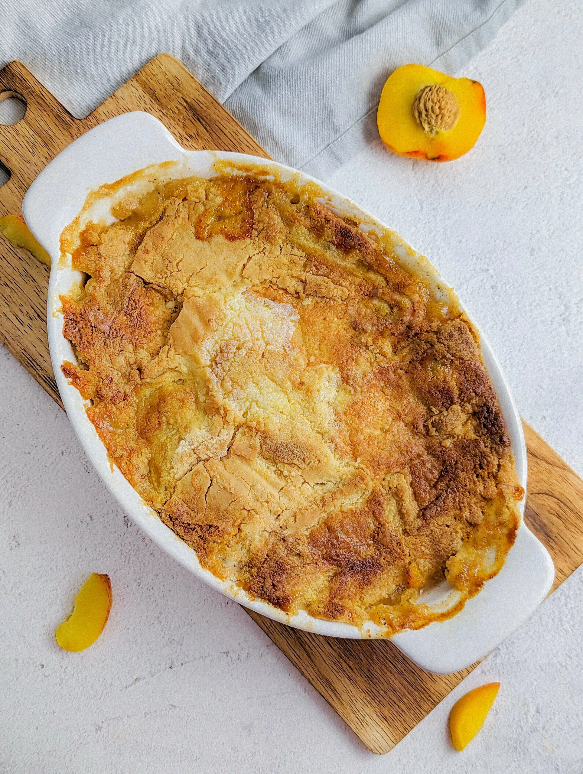 Easy Peach Cobbler with Cake Mix in a serving dish surrounded by peaches.