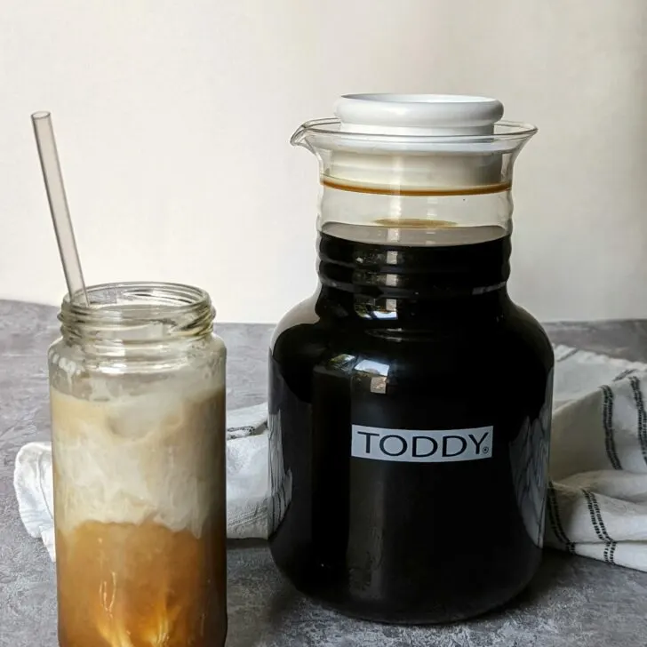 Cold brew concentrate in a toddy next to a cold brew drink.
