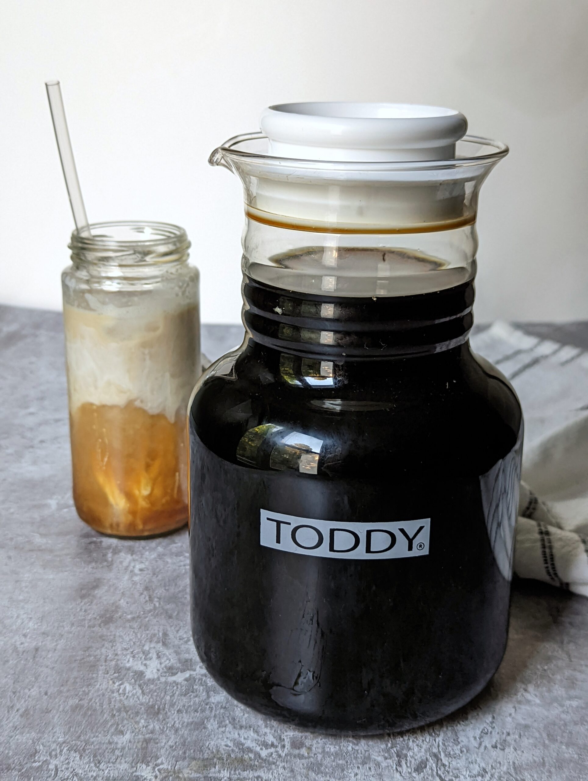 Cold brew concentrate in a toddy next to a cold brew drink.