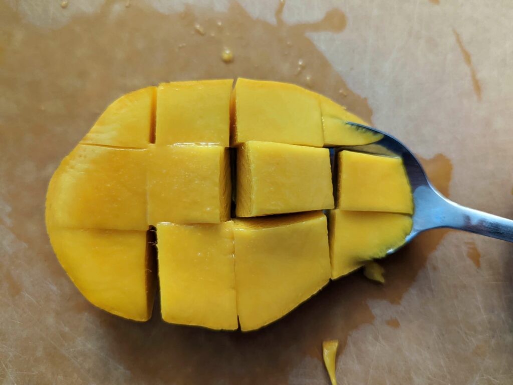 Use a spoon to scoop out the mango cubes.