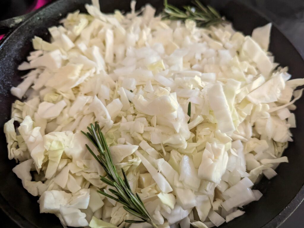Cabbage, onion, and thyme cooking in a skillet.