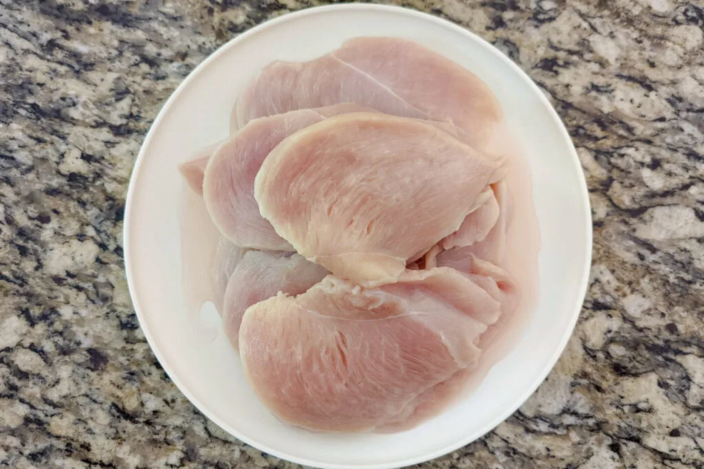 Thinly sliced chicken breasts on a plate.