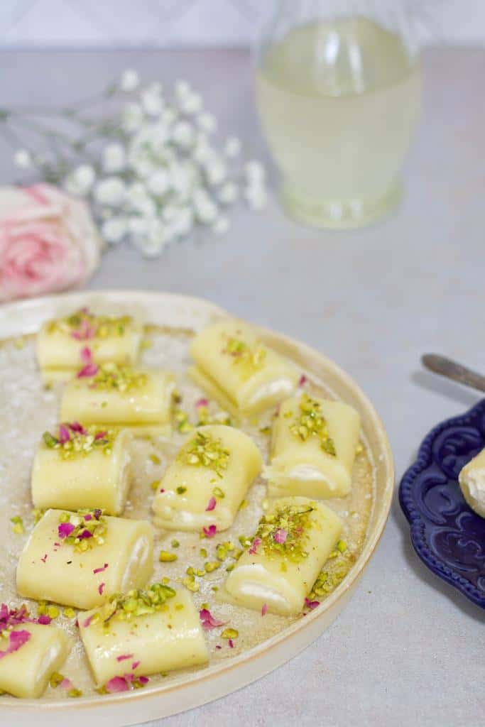 Halawet El Jibn on a plate and garnished with pistachio crumbs.