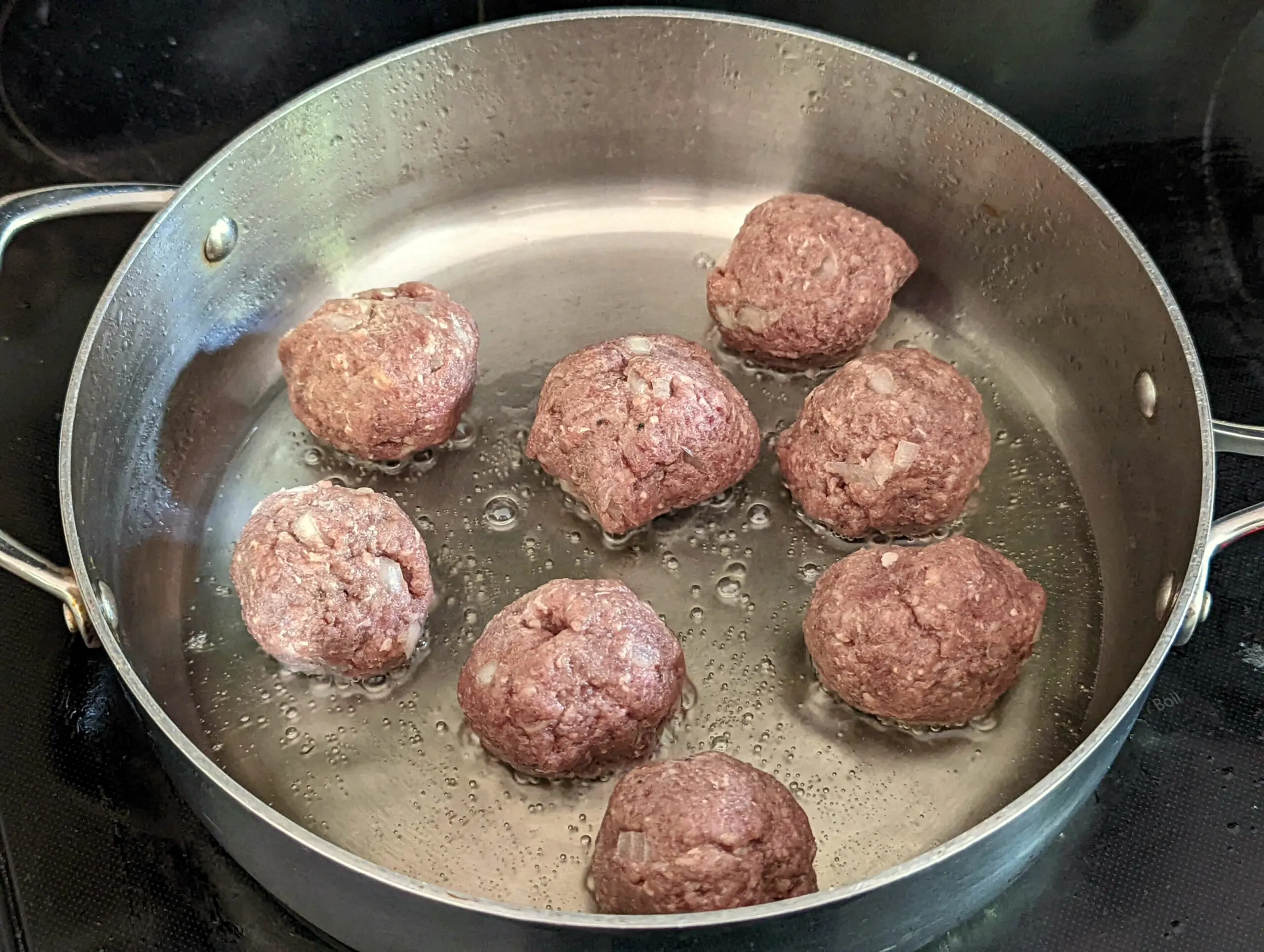 Meatballs searing in the pan.