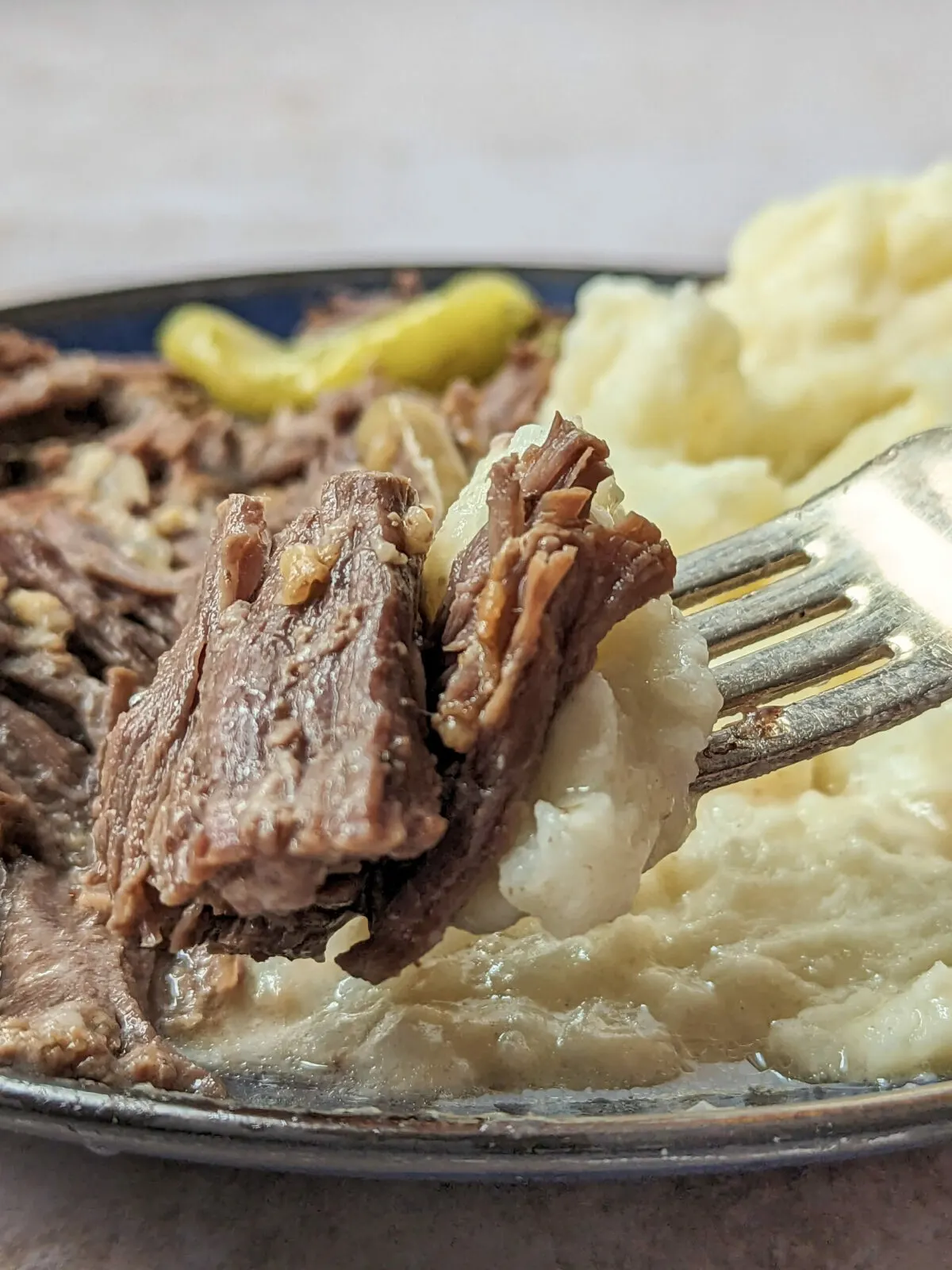 Instant pot mississippi pot roast on a fork with a side of mashed potatoes.