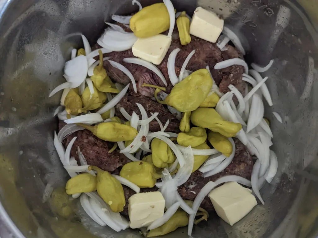 Butter, onions, and peppers added to the chuck roast in the Instant Pot.