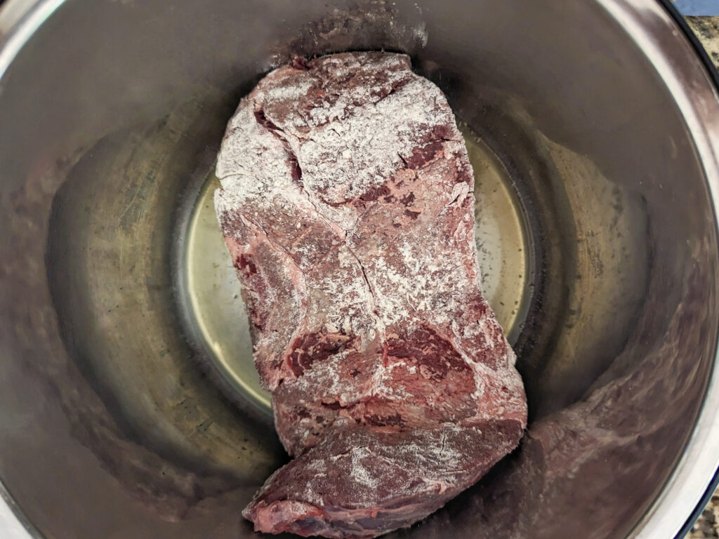 Chuck roast searing in oil in the instant pot.