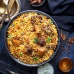 A heaping bowl of mutton biryani topped with cilantro and fried onions.