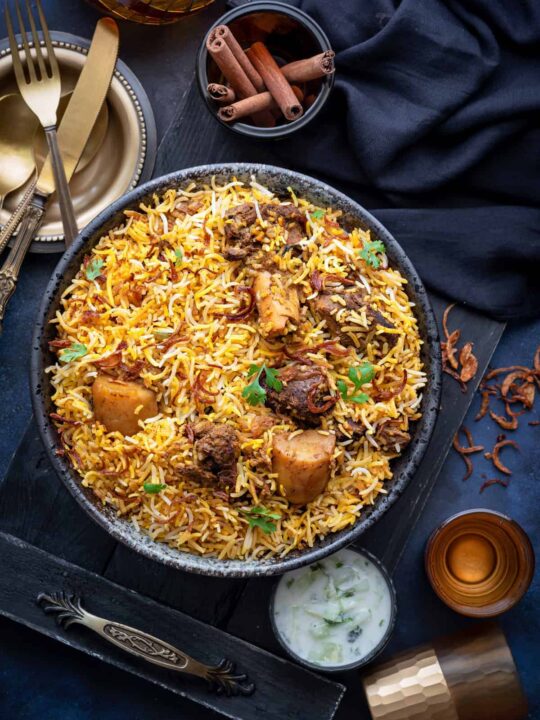 A heaping bowl of mutton biryani topped with cilantro and fried onions.