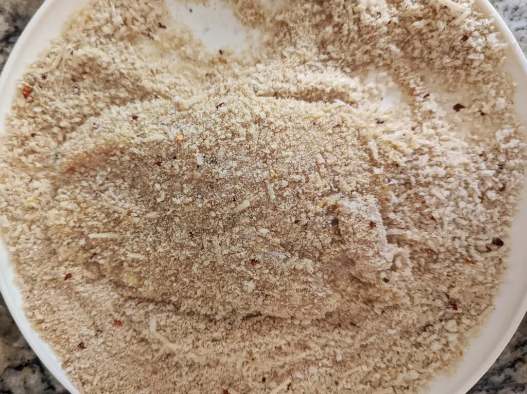 Press the chicken breast into the breadcrumbs.