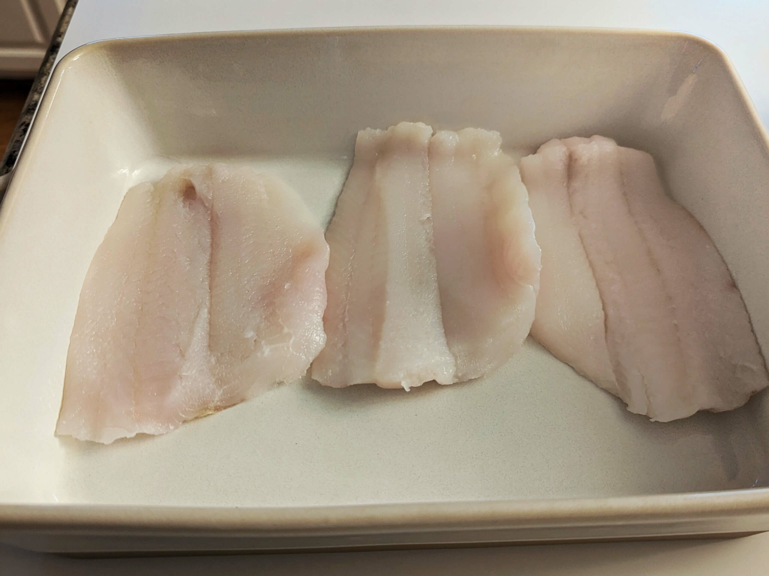Flounder filets lined into a baking dish.