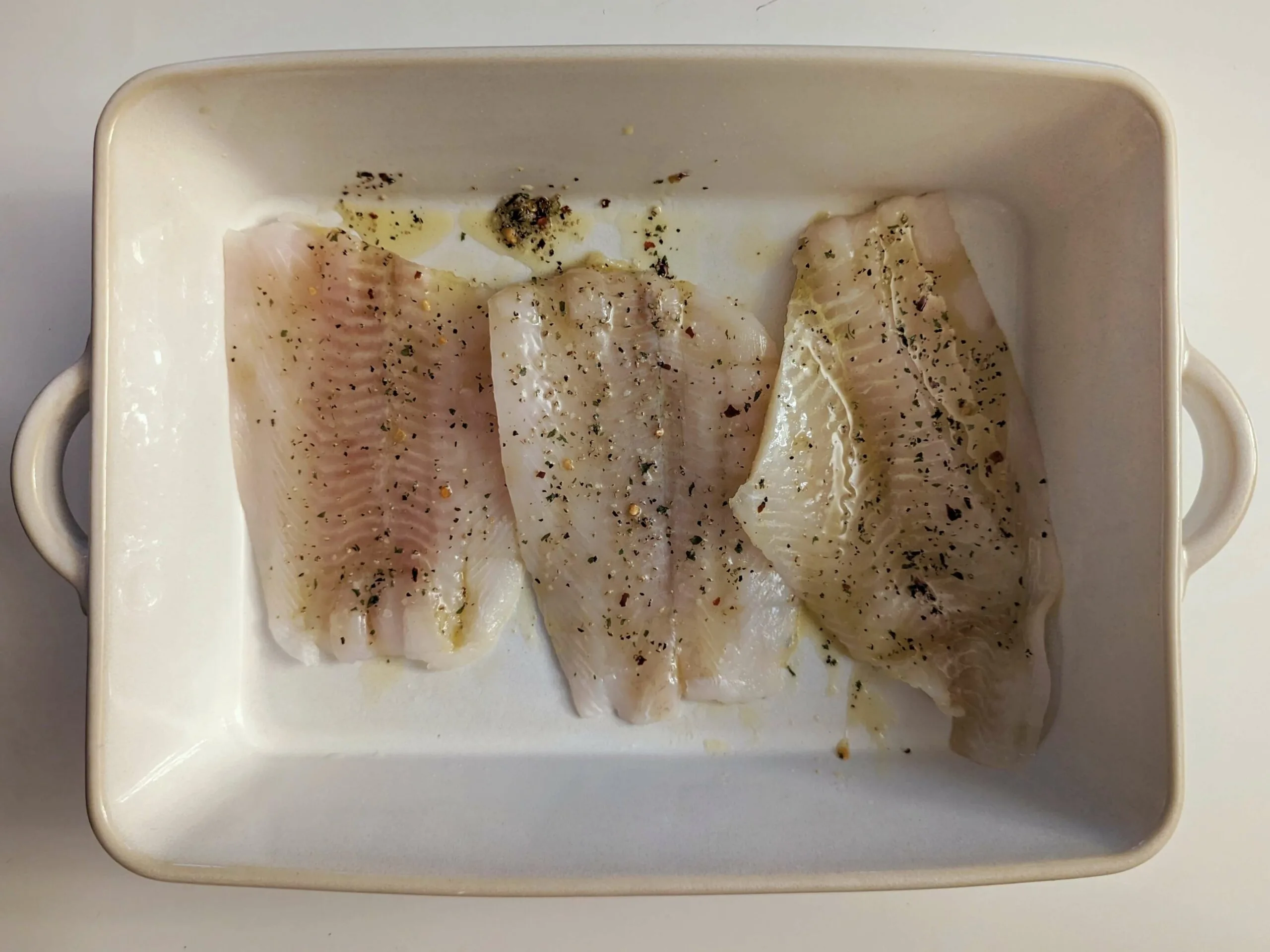 Flounder filets in a baking dish and topped with the butter mixture.