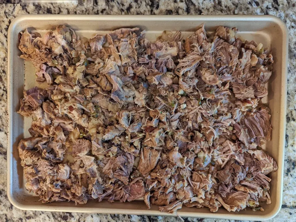 Shred the pork and spread it onto a rimmed baking sheet.
