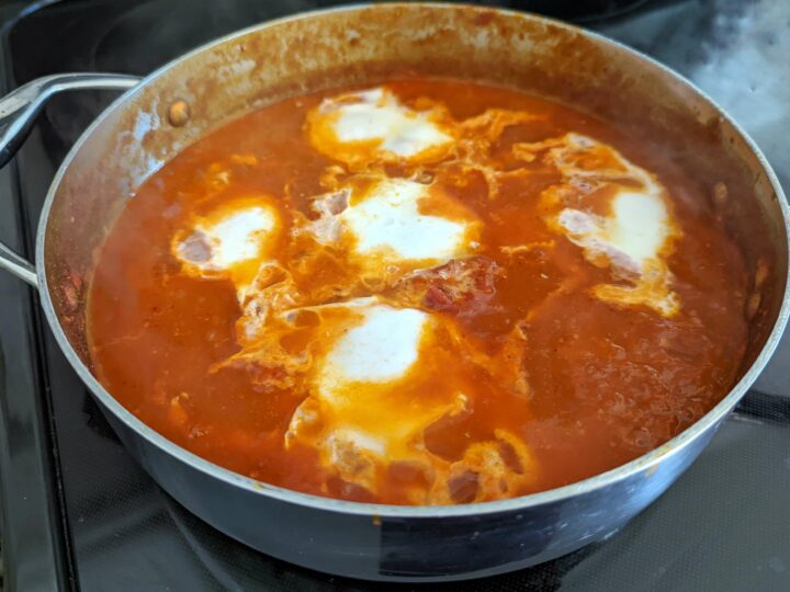Create wells in the tomato mixture and add the eggs.