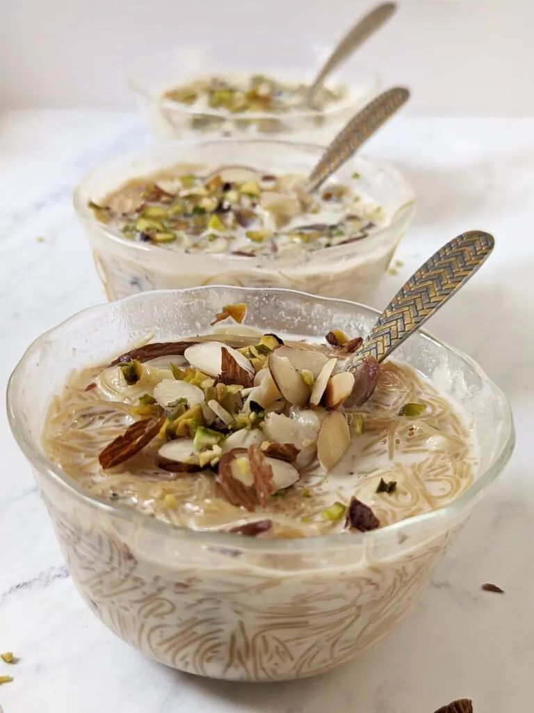 Small bowls with sheer khurma garnished with almond and pisatchio..