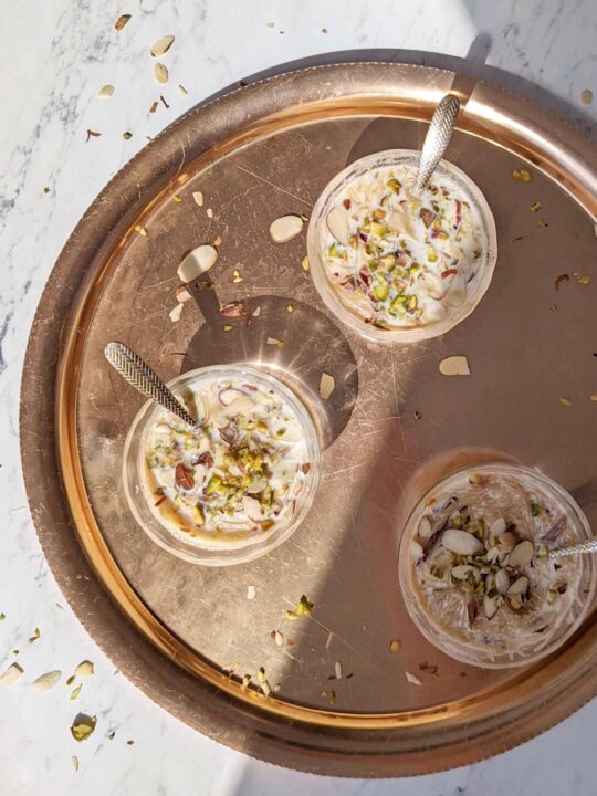 A platter of small bowls with sheer khurma garnished with almond and pisatchio..