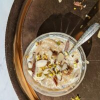 A small bowl with sheer khurma garnished with almond and pisatchio..