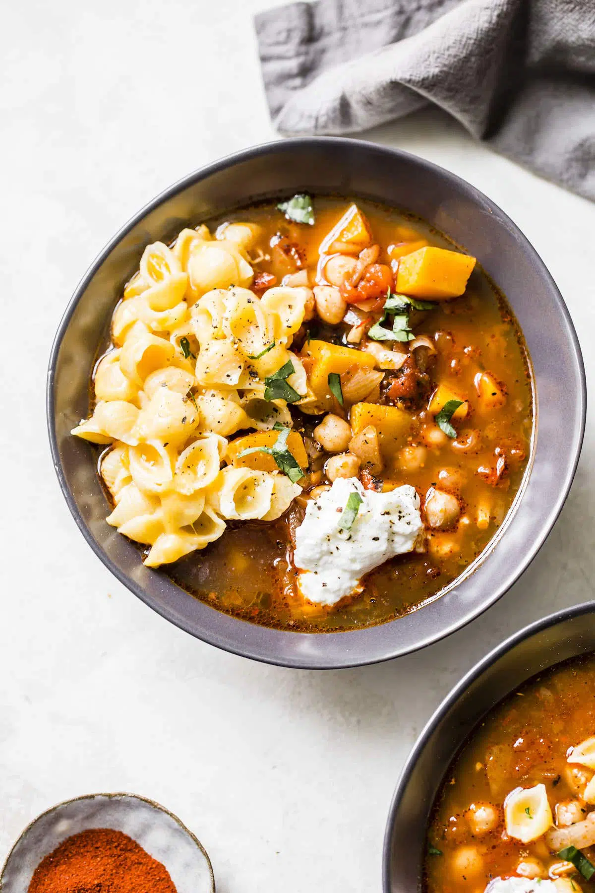 An overhead shot of butternut squash and chickpea chili served with noodles and sour cream.