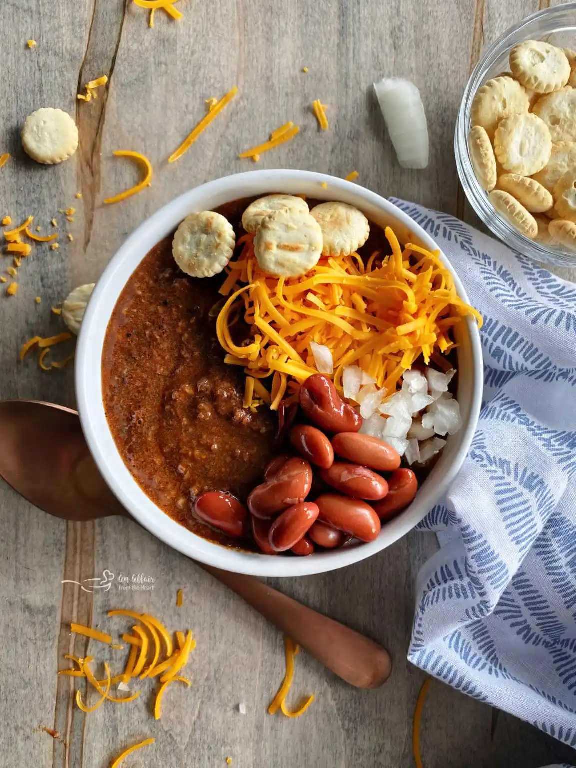 An overhead shot of Cincinnati chili topped with cheddar cheese and oyster crackers.