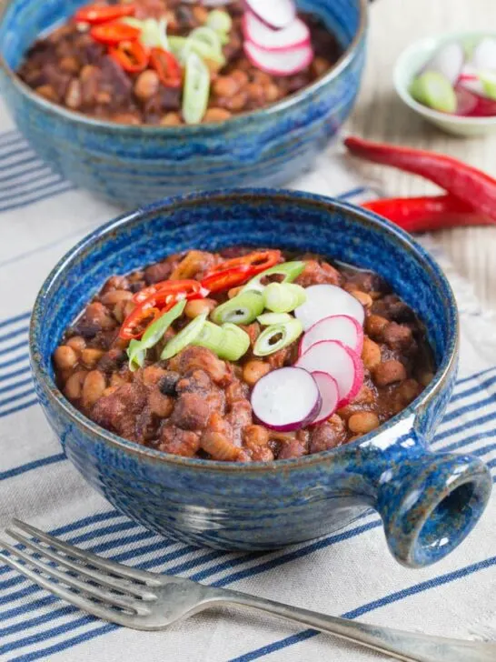 Chili recipe topped with radishes, scallions, and chilies.