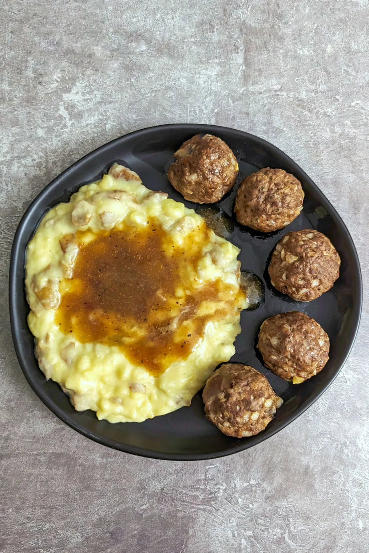 Gravy over mashed potatoes and meatballs.