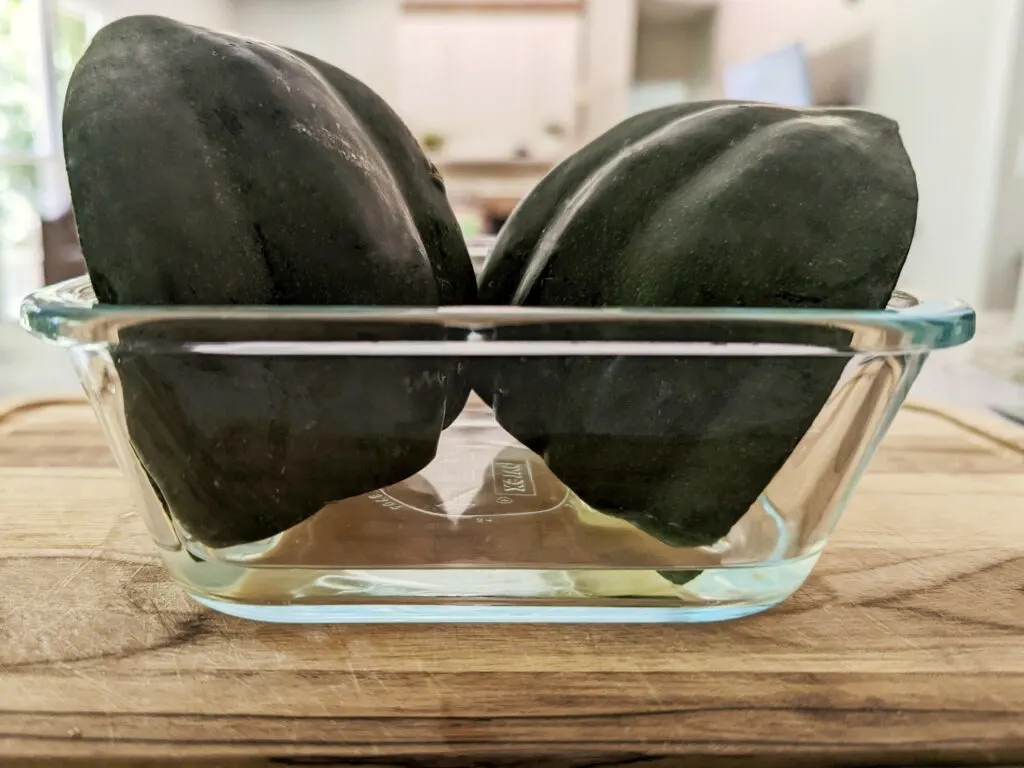 Halved acorn squash in a microwave-safe dish with 1/2 inch of water.