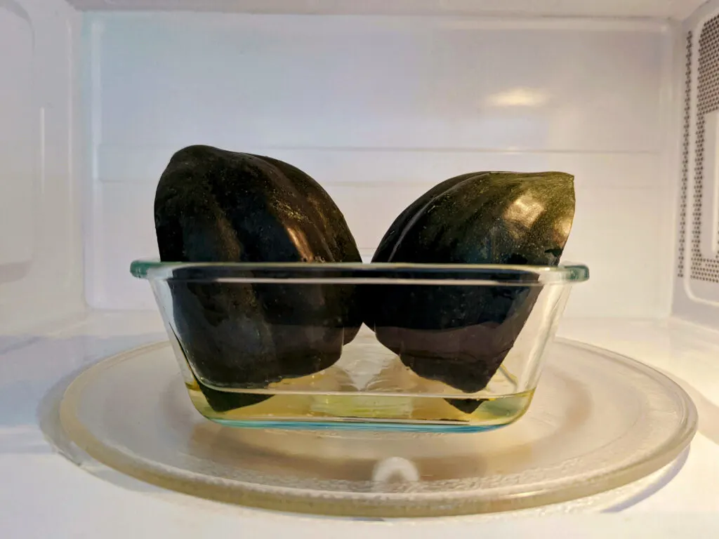 Halved acorn squash in a microwave-safe dish with 1/2 inch of water in the microwave.