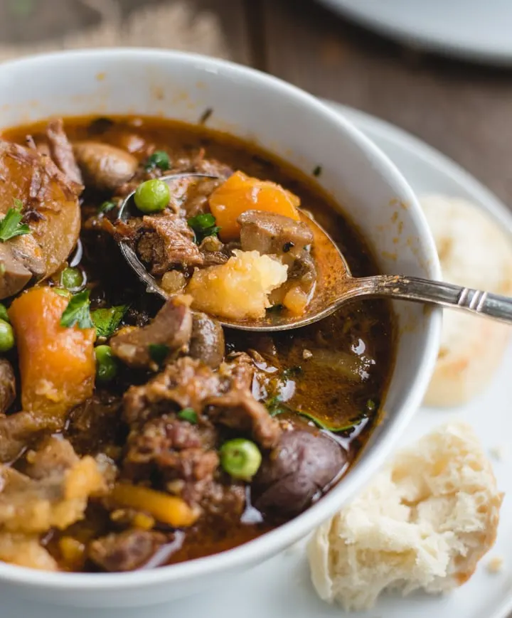 A spoonful of Irish beef stew over a heaping bowl served with fresh bread.