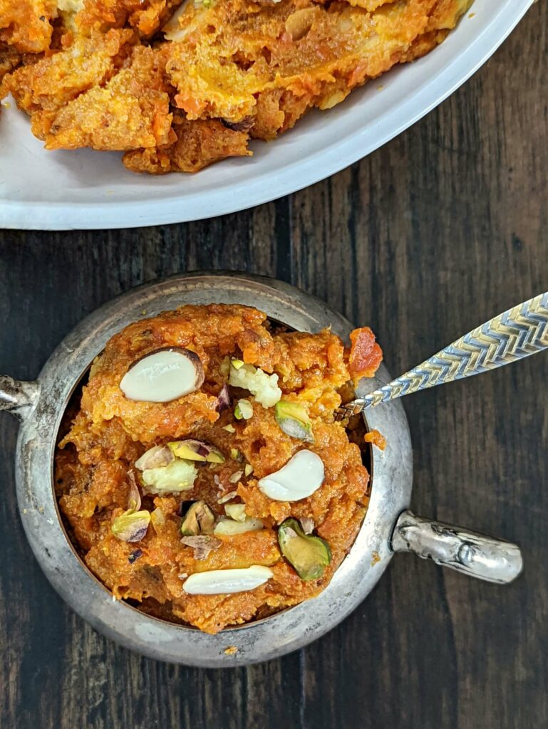 Carrot halwa in a serving dish and garnished with toasted pistachio and almond.