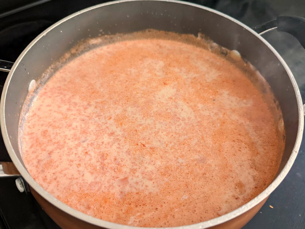 Carrot and milk simmering in a stockpot.