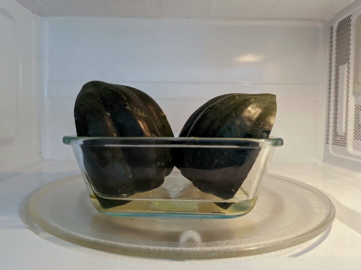 Halved acorn squash in a microwave-safe dish with 1/2 inch of water in the microwave.