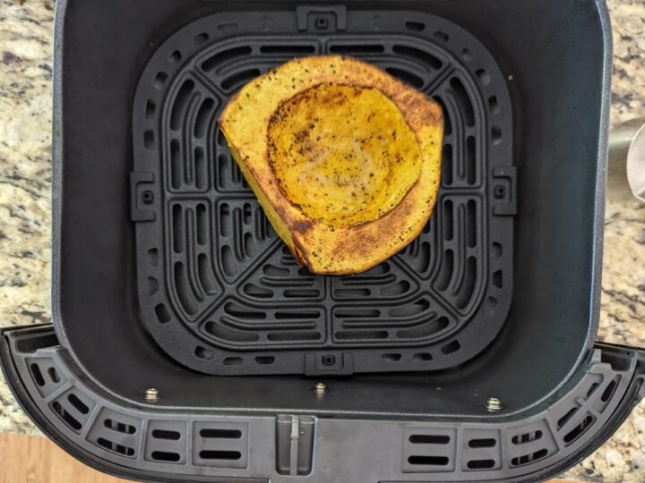 One half of an acorn squash face up in the air fryer.