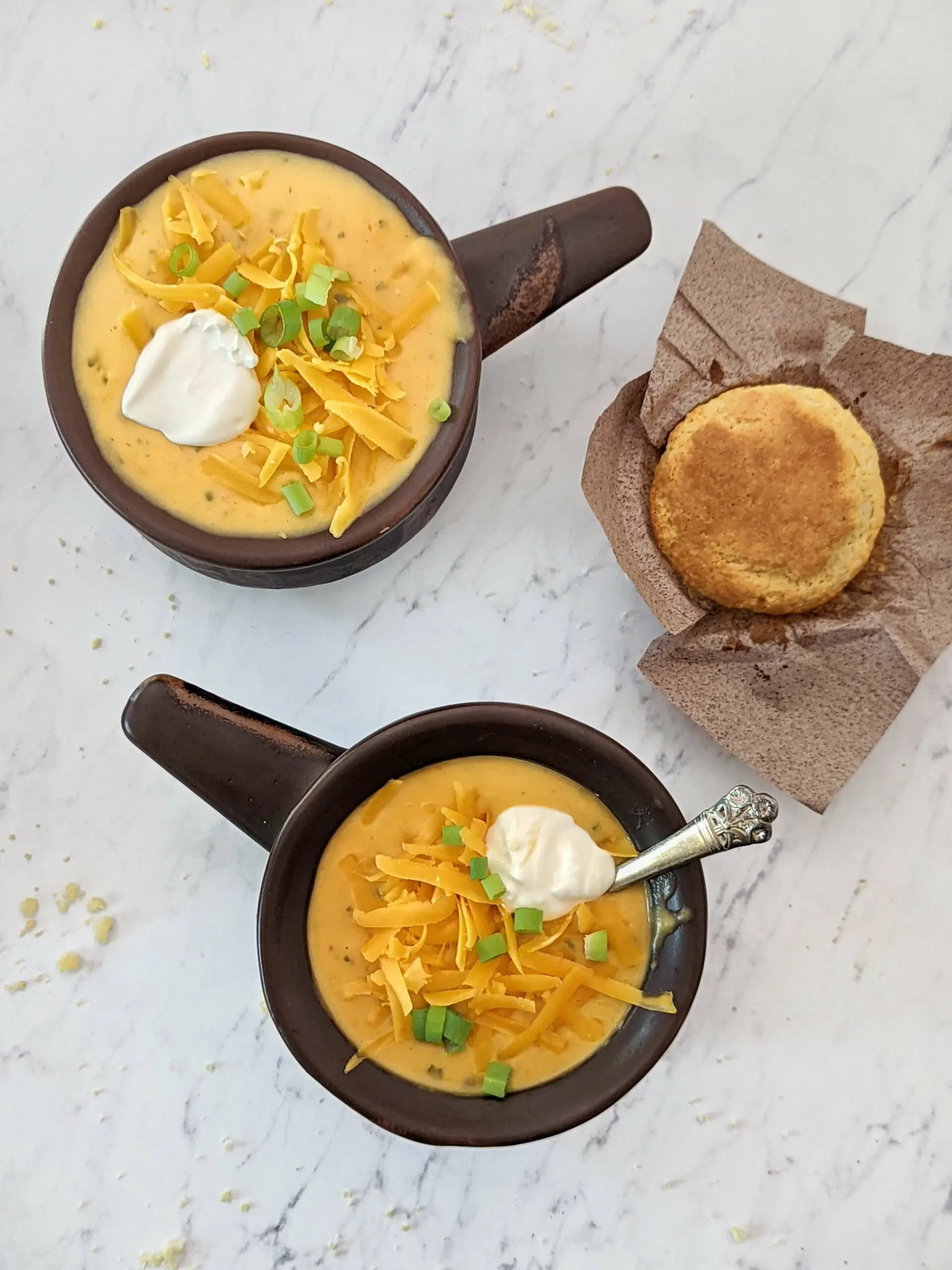 Two soup bowls of potato soup served with corn muffins.