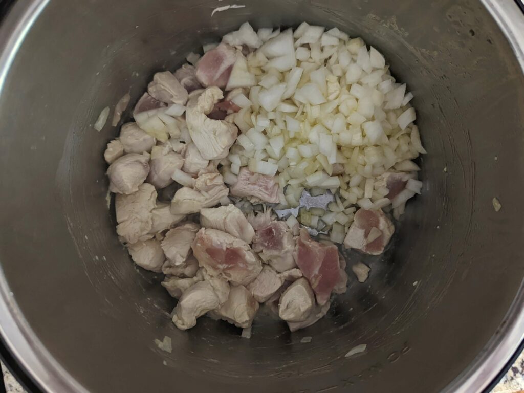Onion and chicken cooking in an Instant Pot.