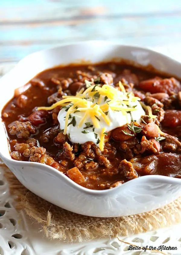 A bowl of slow cooker chili topped with sour cream and cheddar cheese.