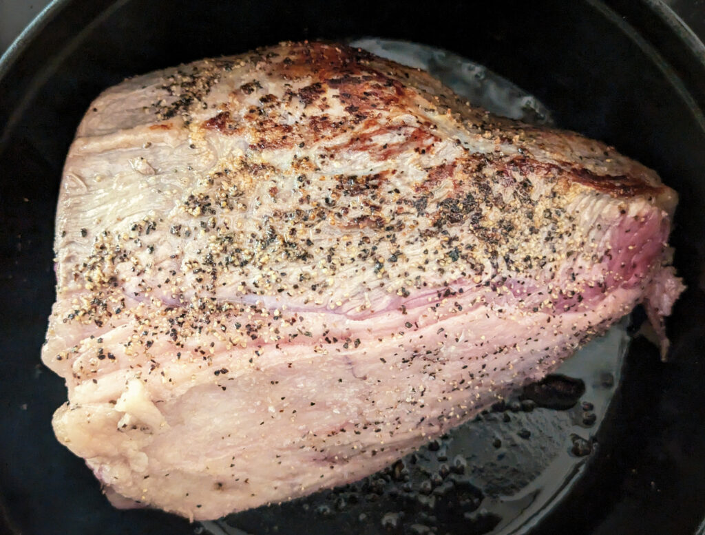 A roast searing in olive oil in a dutch oven.