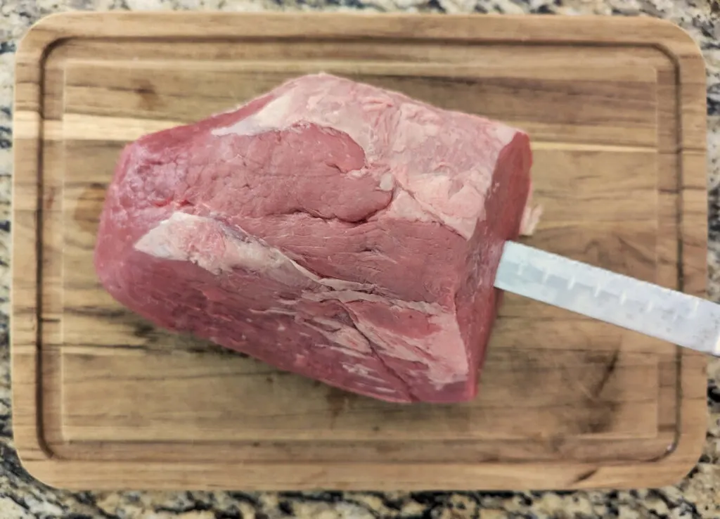 Using a knife to insert into the roast.