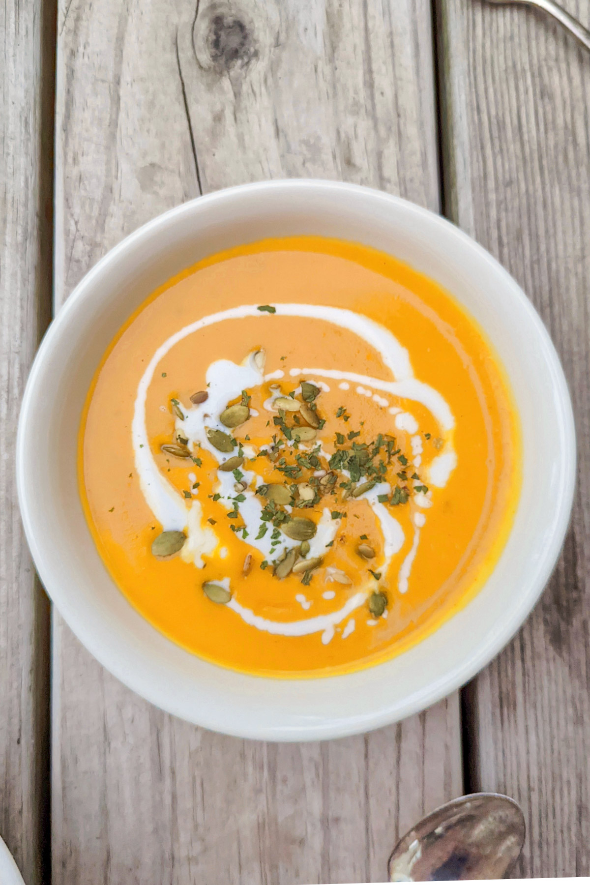 Two bowls of butternut soup topped with pumpkin seeds.