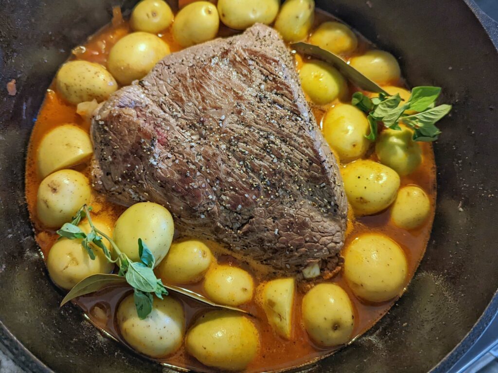 Nestle the roast into the pan and add petite potatoes, fresh oregano, and bay leaves.