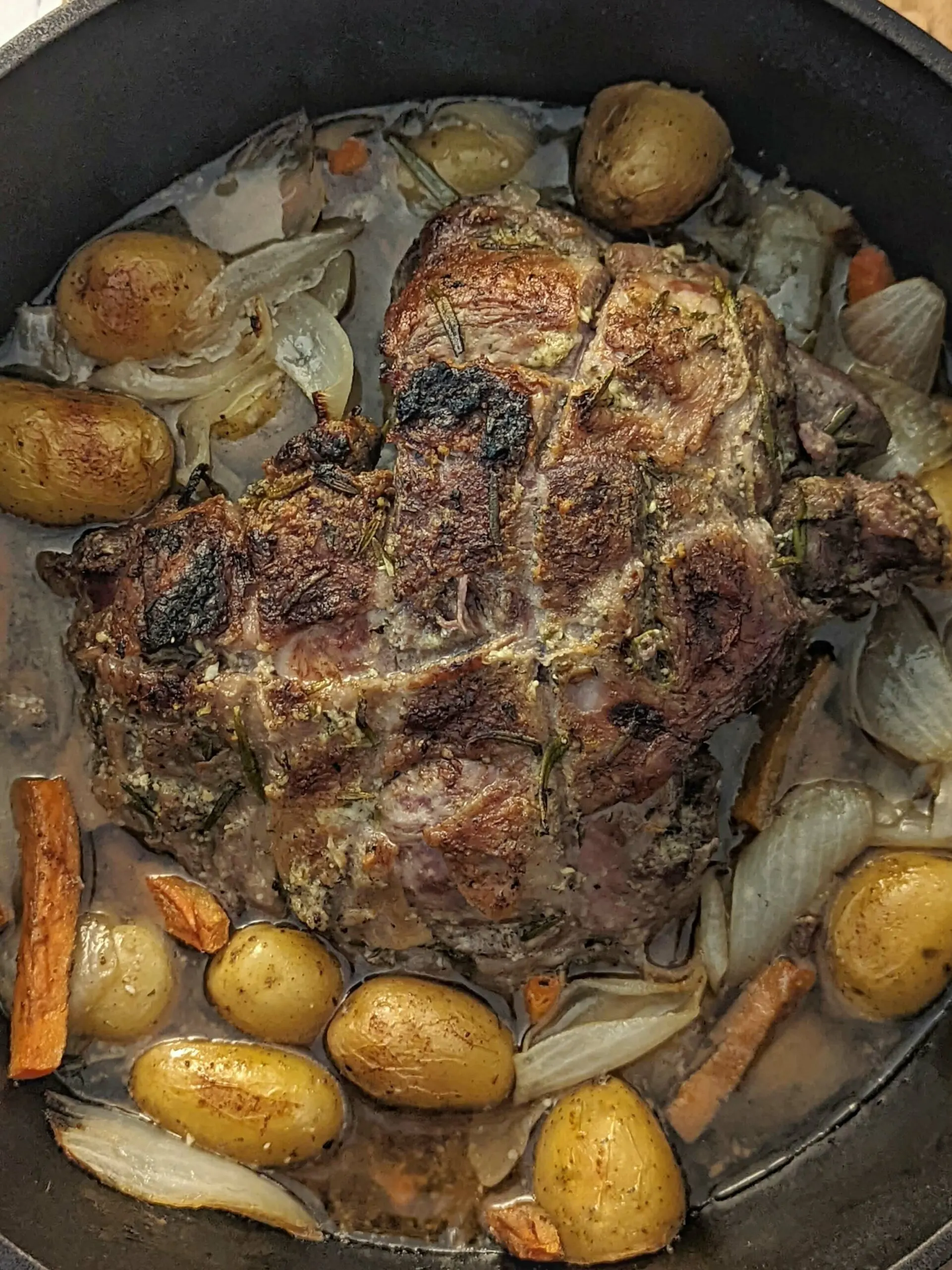 A full Dutch oven of roast with potatoes, carrots, and onion.