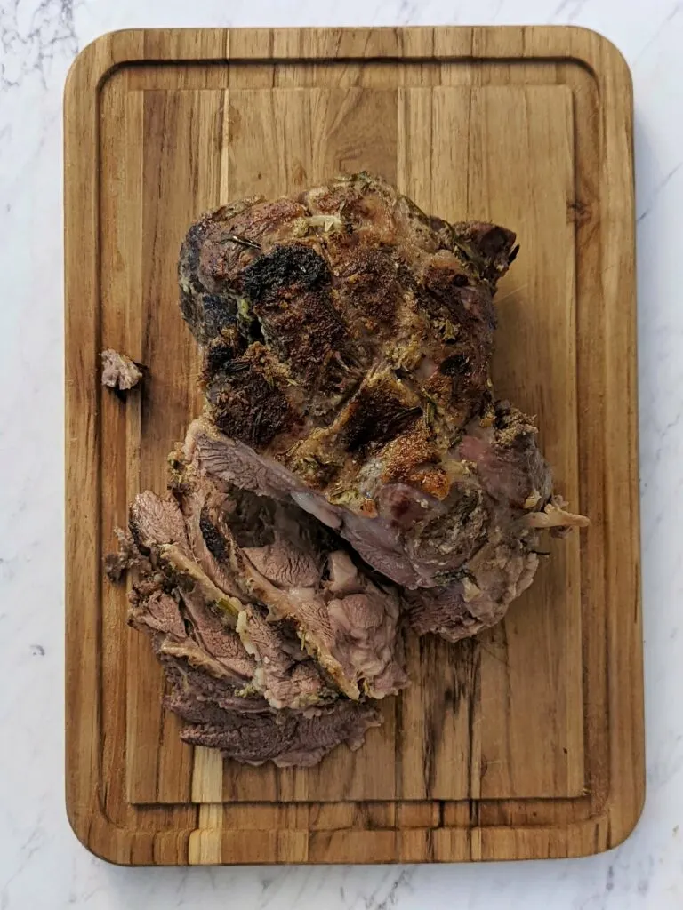Leg of lamb roast sliced on a cutting board.