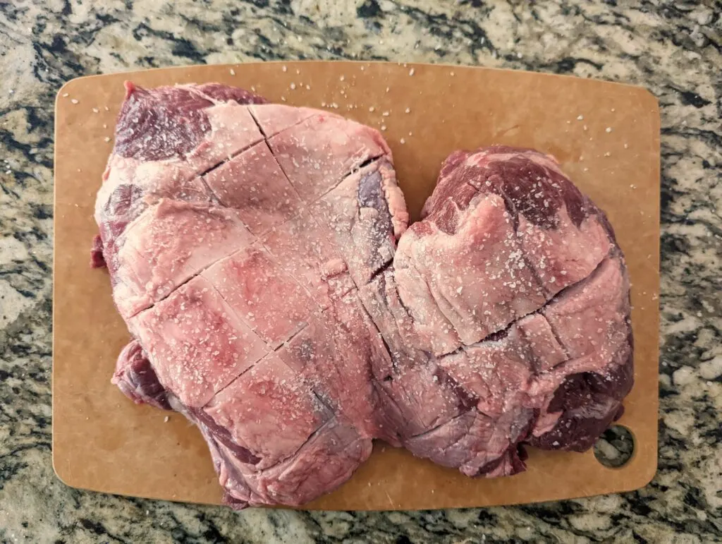 A salted boneless leg of lamb on a cutting board.