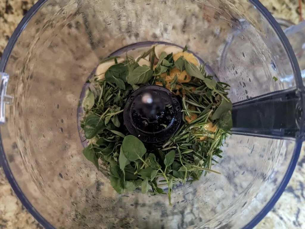 The ingredients for the herb garlic paste in a food processor.