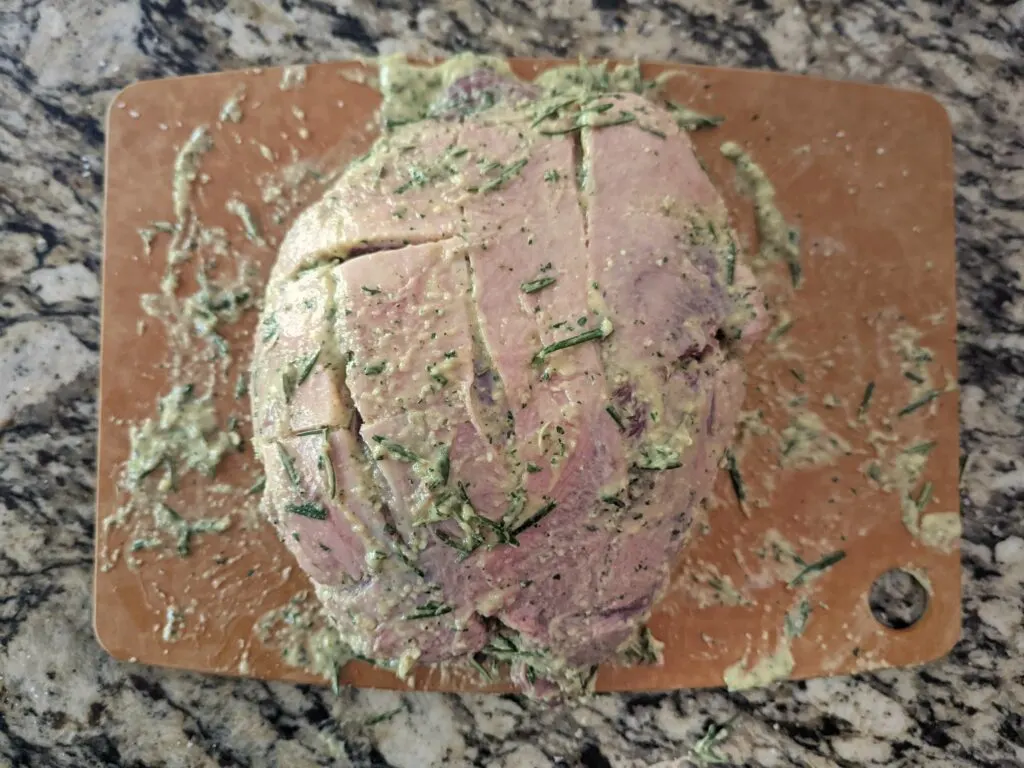 The leg of lamb rolled coated with paste and rolled up.