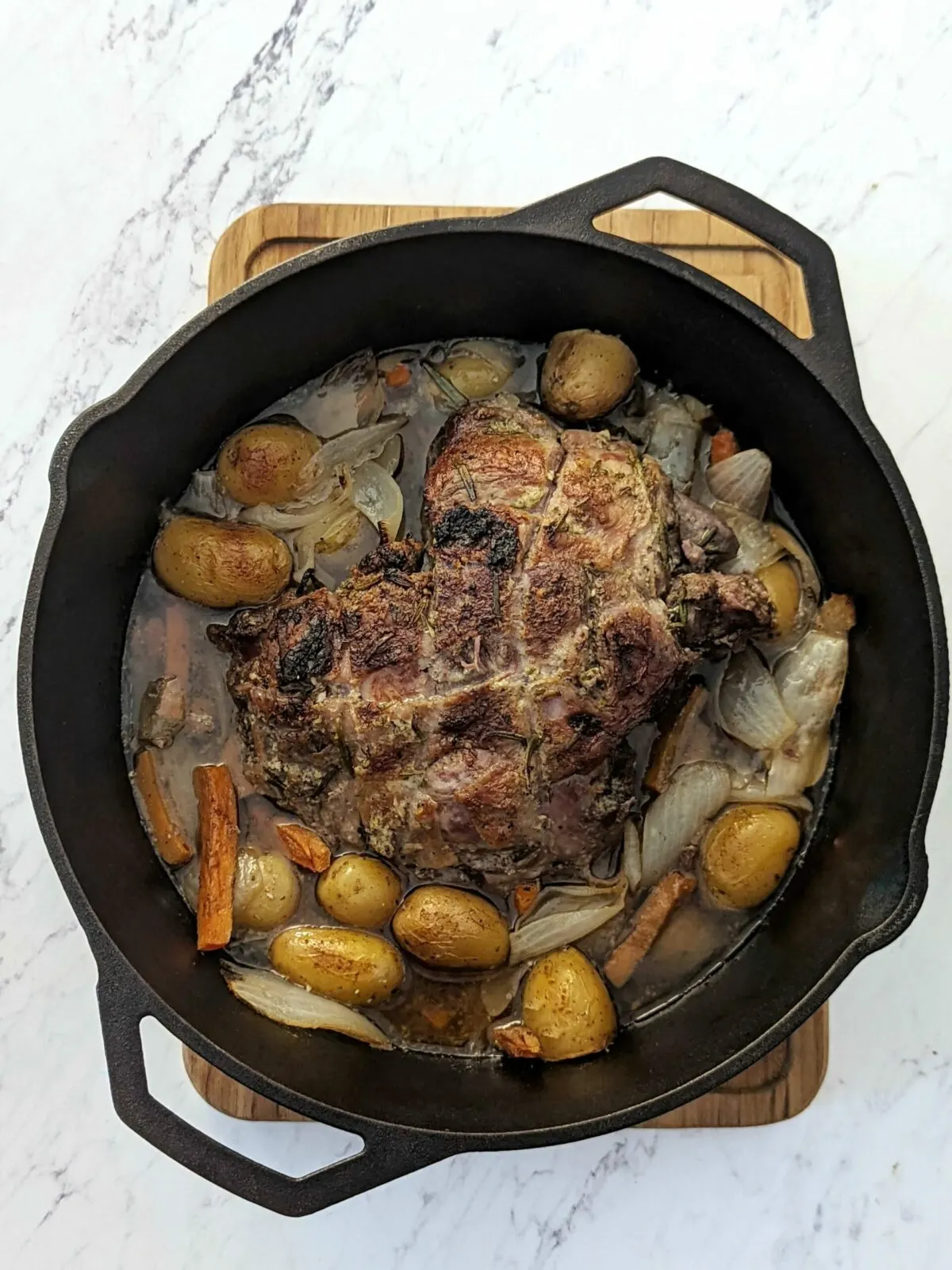 A full Dutch oven of roast with potatoes, carrots, and onion.