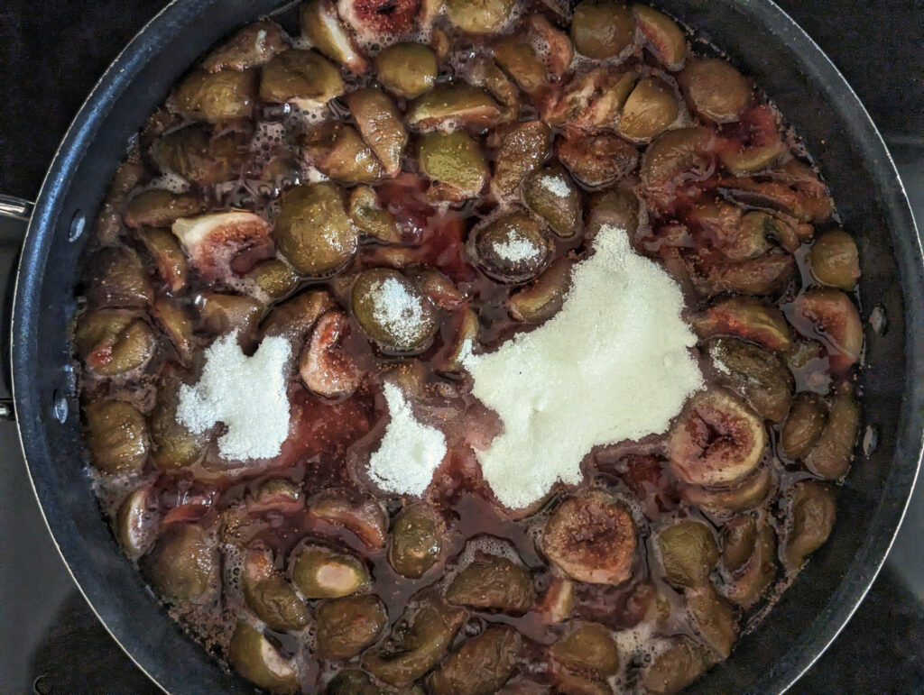 Sugar added to figs simmering in a saute pan.