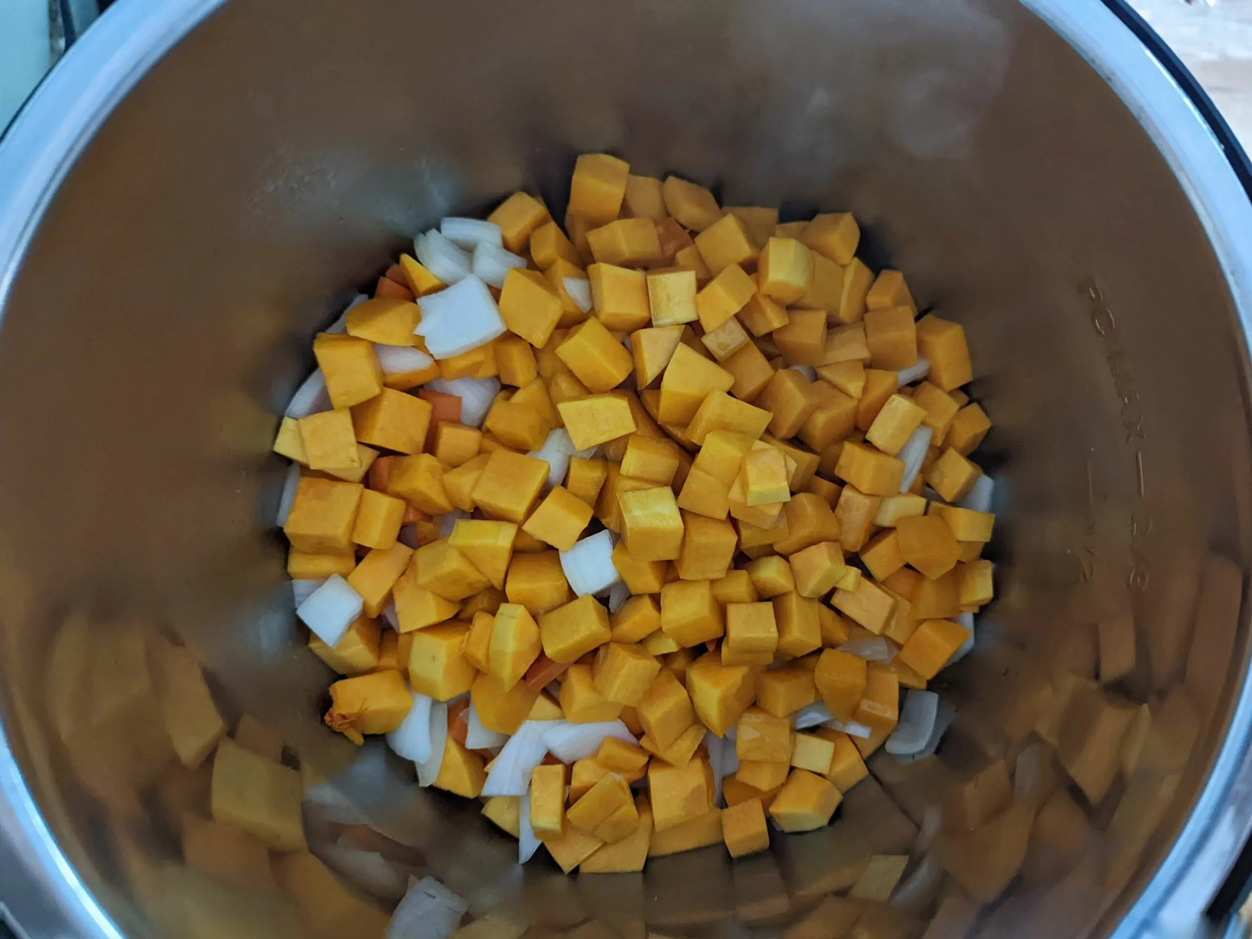 Butternut squash, onion, carrot, and garlic sautéing in an Instant Pot.