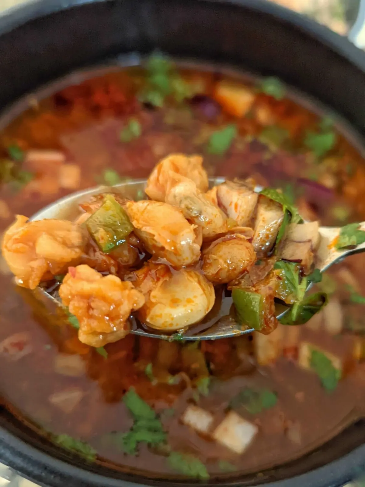 A close up of a spoonful of Instant Pot Pozole Rojo over the bowl.