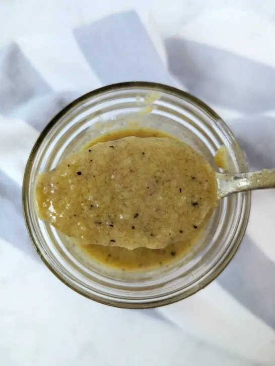 A spoonful of sherry shallot dressing over the jar of dressing.