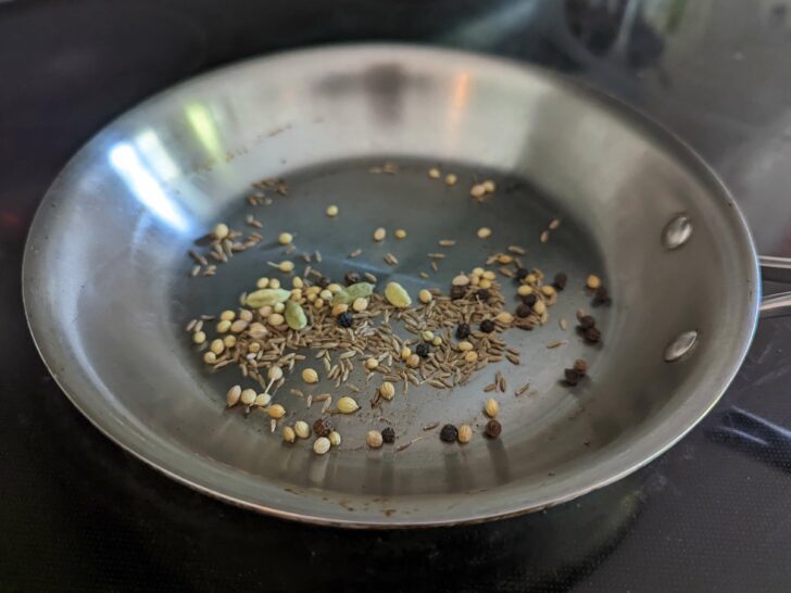 Whole spices toasting in a pan. 